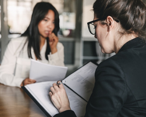 Photo from back of serious businesswoman interviewing and talking with uptight female personnel during job interview 1